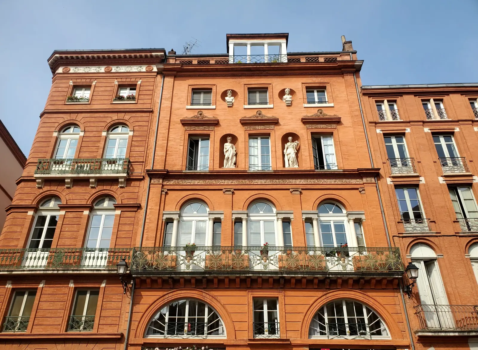 Façade en brique rose d'un immeuble toulousain, place de la Trinité